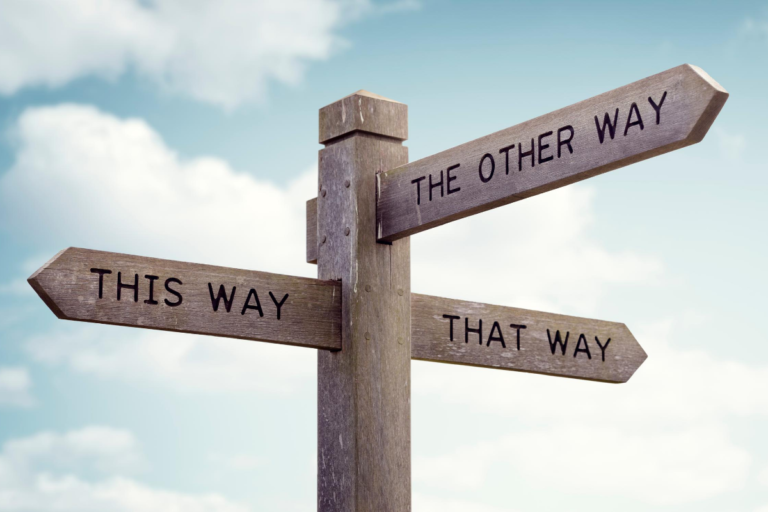 Exploring Our Naaman Moments blog post by heather jeffery with an image of a crossroads with words saying this way or that way wood sign blue sky
